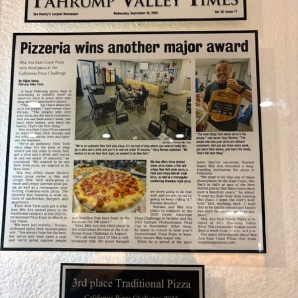 A framed newspaper article about Mia Ava East Coast Pizza winning an award, featuring photos of the restaurant and a pizza.