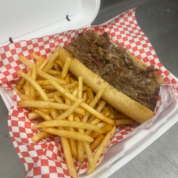 Mia Ava East Coast Pizza's cheesesteak sub with onions and a side of golden french fries.