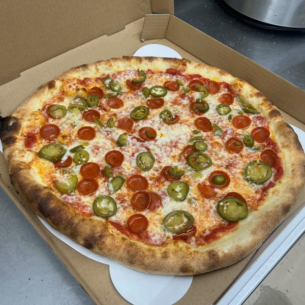 A Mia Ava East Coast Pizza with pepperoni and jalapeños in a cardboard box.