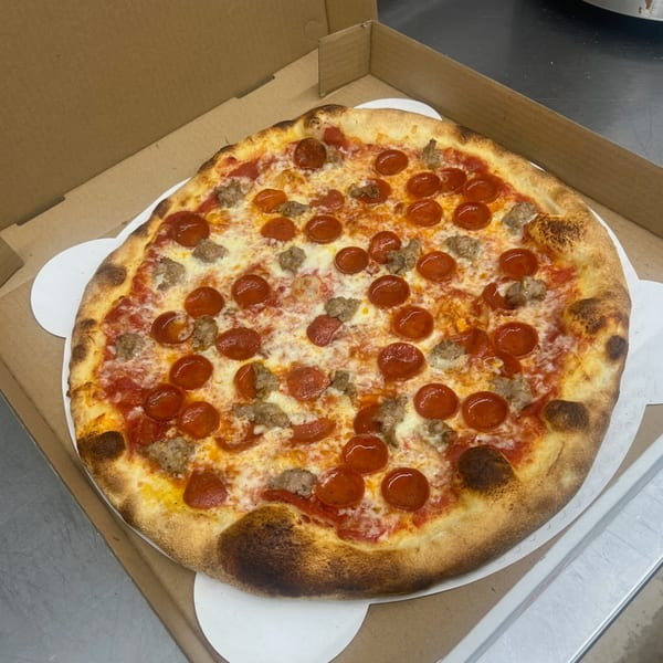 A Mia Ava East Coast Pizza with pepperoni and sausage in a cardboard box.