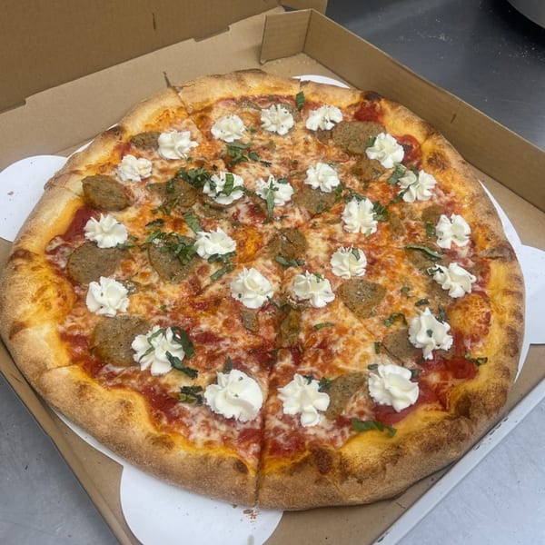Mia Ava East Coast Pizza with sausage, dollops of ricotta, and fresh basil in a pizza box.