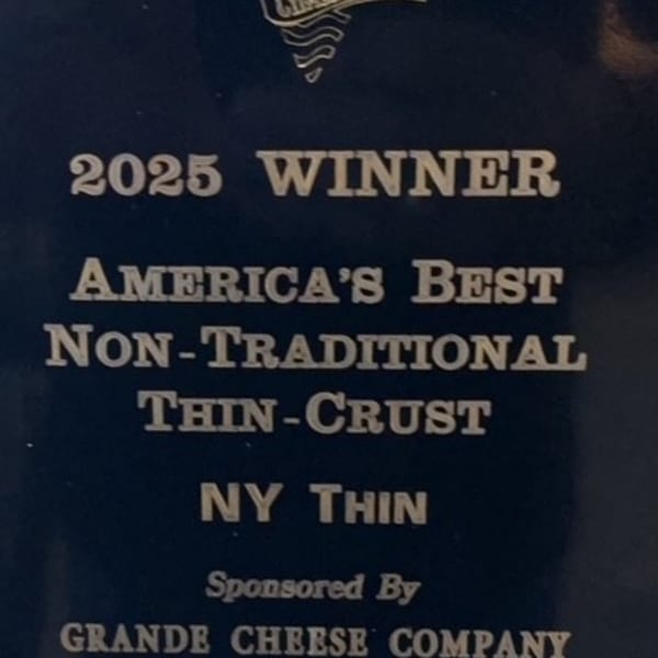 A plaque announcing Mia Ava East Coast Pizza as the 2025 winner for America's Best Non-Traditional Thin-Crust NY Thin.
